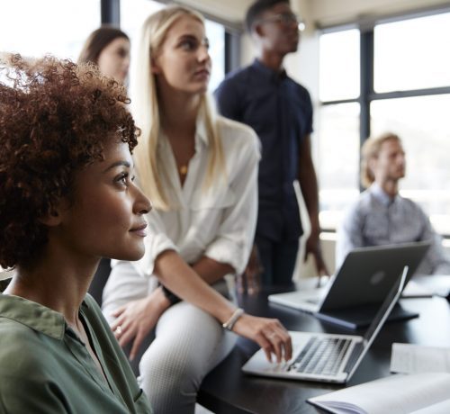 Close up of creative business colleagues listening to an informal presentation in a meeting room